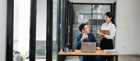 A businessman and businesswoman having a discussion in a modern office setting, showcasing professional work environment and collaboration.の写真素材
