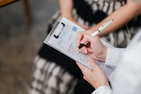 A professional completing a health application form on a clipboard, focusing on the hand holding a pen.の写真素材