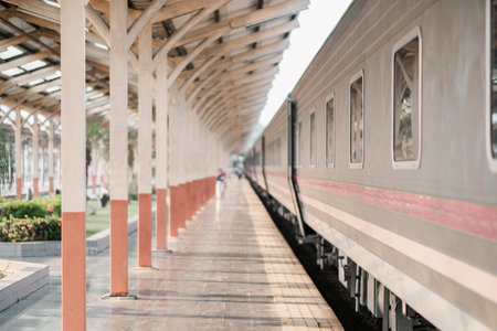 A serene vintage train station platform with empty railway tracks and a sunlit covered walkway, capturing a nostalgic travel atmosphere.の写真素材