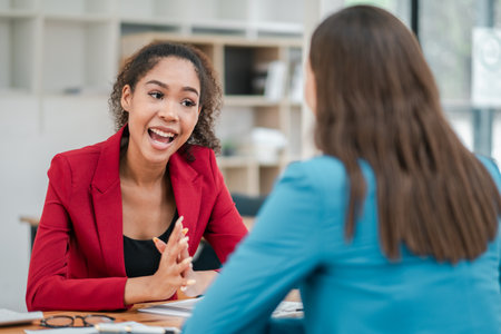 Two women engaged in a professional business meeting, discussing work in a modern office environment.の写真素材