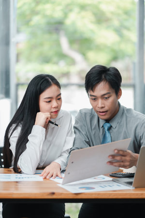 Two business professionals reviewing documents together in a bright, modern office environment.の写真素材