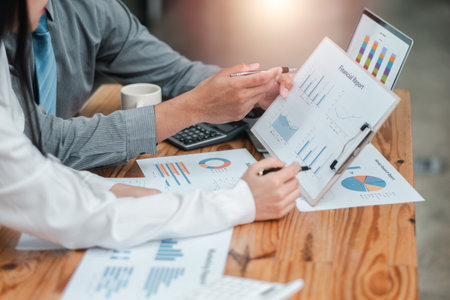 Professionals analyzing financial reports and charts during a business meeting, focusing on data and strategy.の写真素材