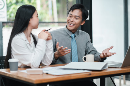 Two colleagues engaged in a productive business meeting, discussing ideas and strategies in a modern office environment.の写真素材
