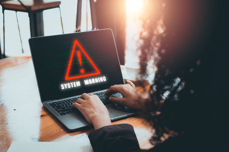 Person using laptop with system warning hacked alert concept displayed on screen, highlighting cybersecurity threats.の写真素材