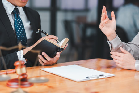 Professional lawyer consulting with a client, discussing legal documents and providing advice in a modern office setting.の写真素材