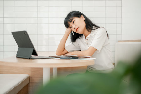 A young woman in a white shirt uses a tablet in a modern cafe with a minimalist design and white...