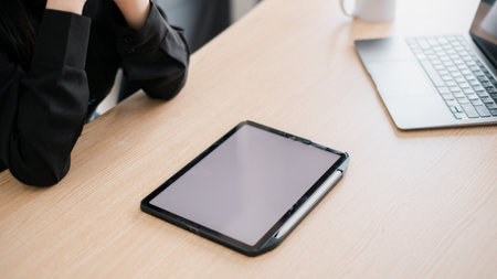 A sleek tablet and laptop on a wooden desk, showcasing a modern and minimalist workspace environment.の写真素材