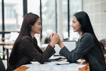 Two professional women in a modern office setting, sharing a positive and collaborative moment during a business meeting.の写真素材
