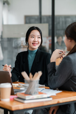 Two women in a modern office setting engaged in a professional business meeting, discussing ideas and collaborating.の写真素材