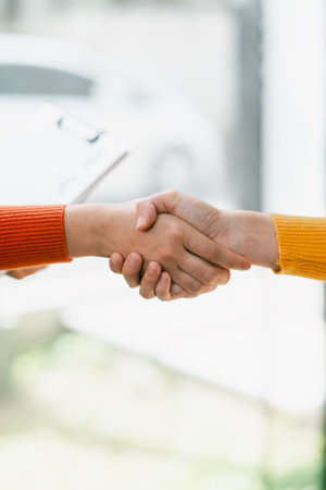 A close-up image of two individuals shaking hands, wearing colorful sweaters, representing cooperation and teamwork.の写真素材