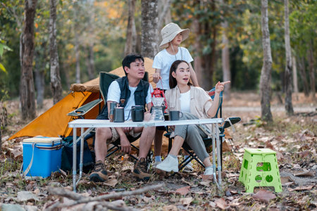 A family bonding experience in nature, enjoying a camping trip with a tent and outdoor equipment in a serene forest setting.の写真素材