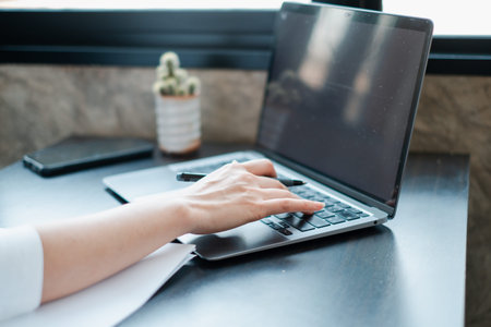 A person typing on a laptop in a bright office, highlighting technology and productivity in a...