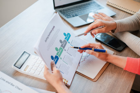 Professionals reviewing sales data and strategy documents with charts and graphs in a collaborative office environment.の写真素材