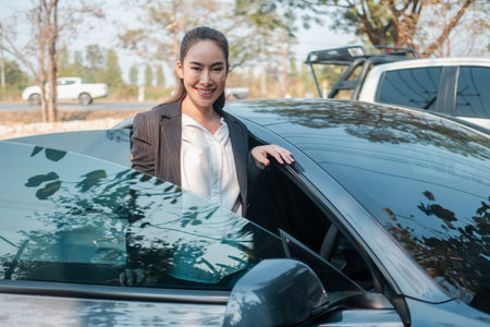 Smiling businesswoman stepping out of a sleek car, showcasing confidence and success in a professional setting.の写真素材