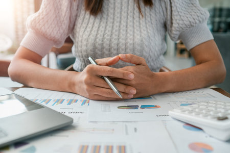 Close-up of a woman reviewing financial documents and charts, emphasizing analysis and business...