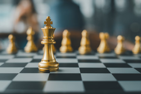 Close-up of golden chess pieces on a chessboard, highlighting the king in a strategic game setting.の写真素材