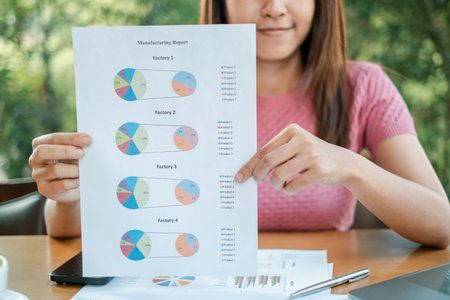 Businesswoman holding a manufacturing report with pie charts, showcasing data analysis and strategic...