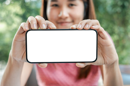 Close-up of a woman holding a smartphone with a blank screen, perfect for mockups and design presentations.の写真素材