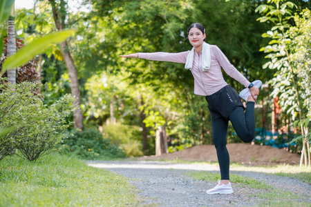 Woman in athletic wear stretching in a park, showcasing fitness and wellness in a natural outdoor setting.の写真素材