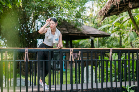 A woman enjoys a refreshing drink on a balcony surrounded by lush tropical greenery.