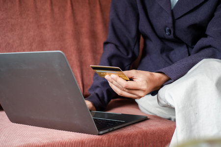 Close-up of a person using a laptop and credit card for online shopping, highlighting e-commerce and digital transactions.の写真素材