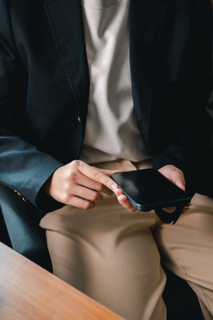 Close-up of a person in business attire using a smartphone, highlighting modern communication and productivity.の写真素材