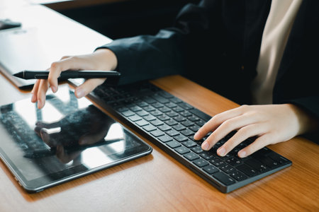 Hands using a tablet and keyboard, ideal for digital design, creativity, and modern office work settings.の写真素材