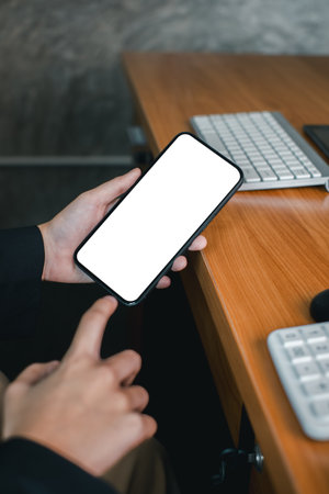 Close-up of a person holding a smartphone with a blank screen, ideal for mockups or design presentations.の写真素材