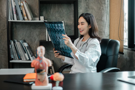 A female doctor examines an X-ray in a contemporary medical office, showcasing healthcare professionalism and modern medical practices.の写真素材