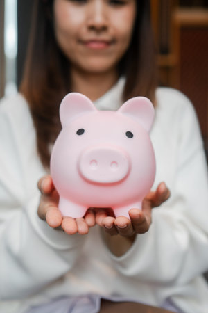 Close-up of a woman holding a pink piggy bank, representing savings and financial planning.の写真素材