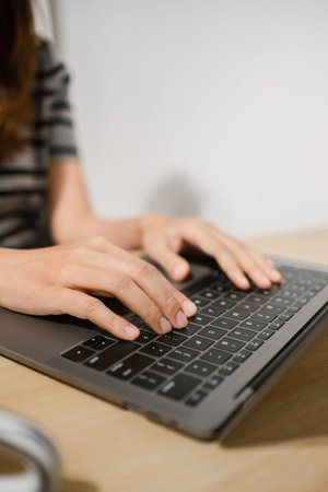Hands typing on a laptop keyboard, showcasing productivity and technology in a modern workspace...