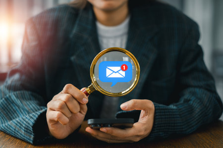 Business professional using a smartphone and magnifying glass to analyze email marketing strategies for effective communication.の写真素材