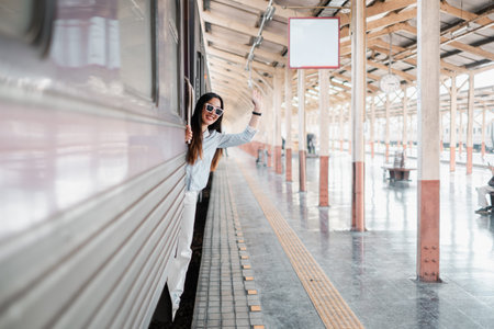 Woman waves from a train at a vintage railway station with wooden beams and reflections on the...