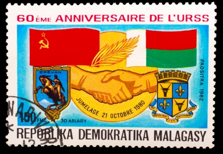 MALAGASY - CIRCA 1982: A stamp printed in MALAGASY, Democratic Republic of Malagasy, Soviet flag and Malagasy, handshake hand, circa 1982のeditorial素材