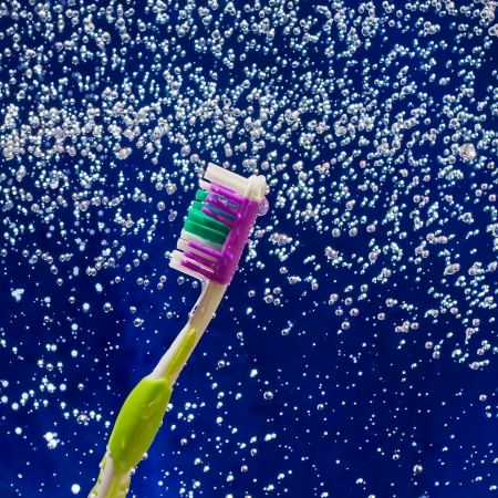 toothbrush in the spray and drops on blue water textureの写真素材