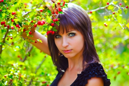 portrait of a woman on nature green background with red berries thoughtful lookの写真素材