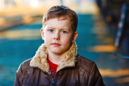 homeless sad blond abandoned alone child is boy on street in jacketの写真素材