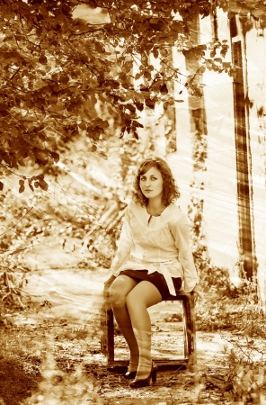 retro sepia photo curly girl woman sitting on box next to abandoの写真素材