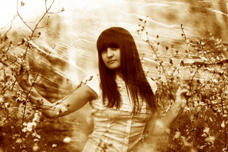 retro sepia photo girl spring holding a branch of cherry blossomの写真素材