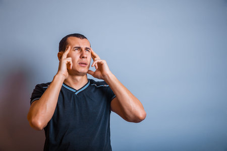 30 years old man of European appearance headache on a gray background