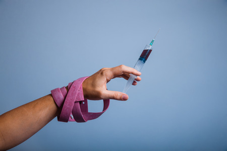 hand wound with a tourniquet holding syringe, drug addict の写真素材