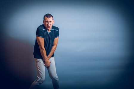 European the man holding his hands over groin in pain on a grayの写真素材