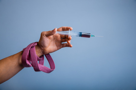 hand with plait holding syringe drug on grayの写真素材