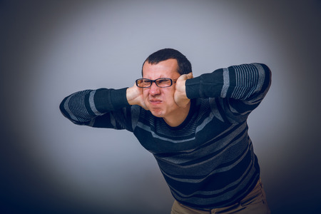 European-looking male covering his ears with  hands brunetの写真素材