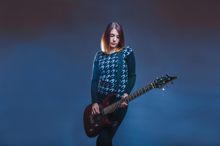 European-looking girl playing guitar on a gray backgroundの写真素材