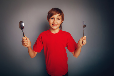boy teenager European appearance in a red shirt holding a spoonの写真素材
