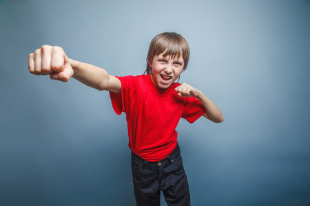 European-looking boy of ten years shows a fist, anger, danger, mの写真素材