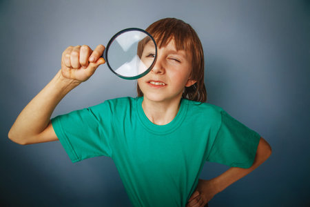 European-looking boy of ten years a joke, looking through a magn