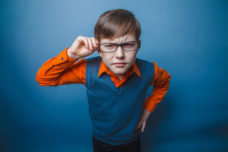 European-looking boy of ten years in glasses, anger, resentment against the gray 