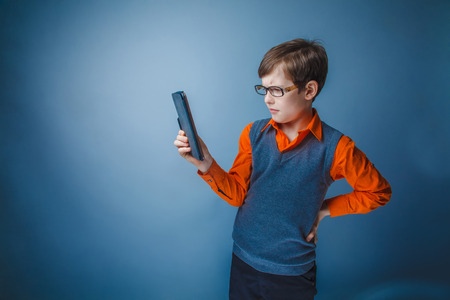 European-looking boy of  ten years in glasses  looks at the plate on a gray の写真素材
